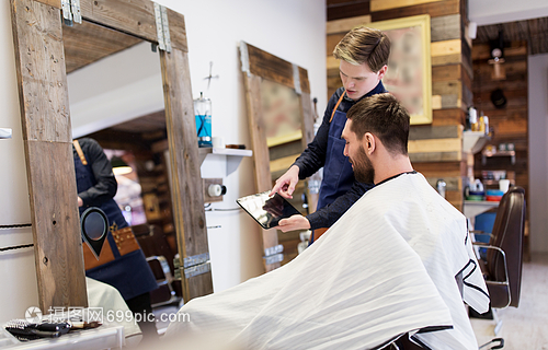 美容技术人的理发师理发师展示平板电脑电脑给人理发店理发师向理发师展示平板电脑