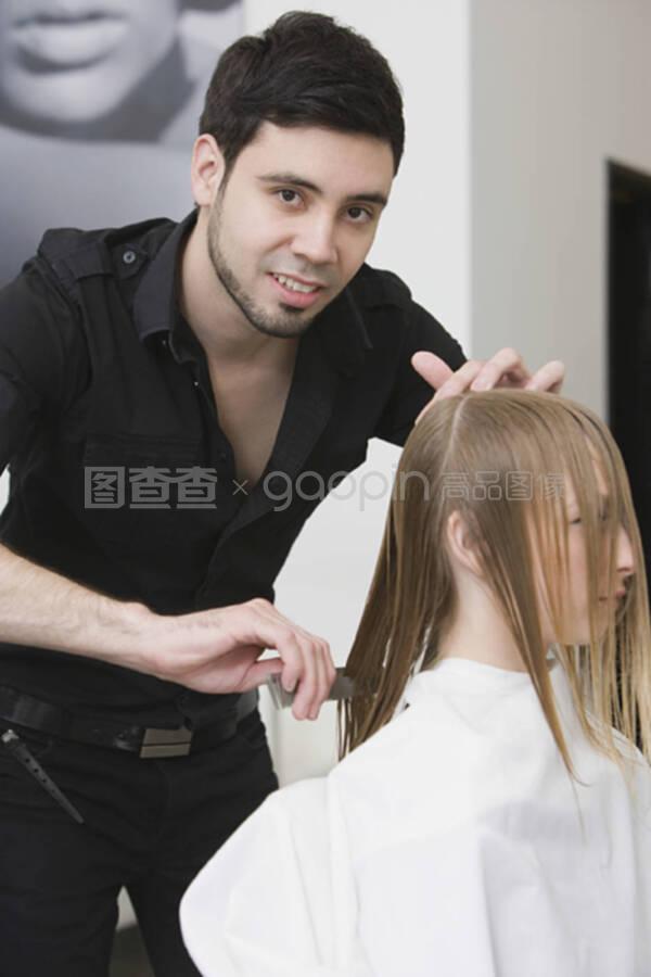 发型师在发廊给顾客理发前分头发